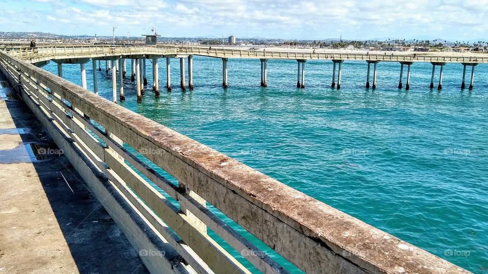 Pacific waters through pylons and railing of the Free People's Fishing Pier in Ocean Beach, CA.