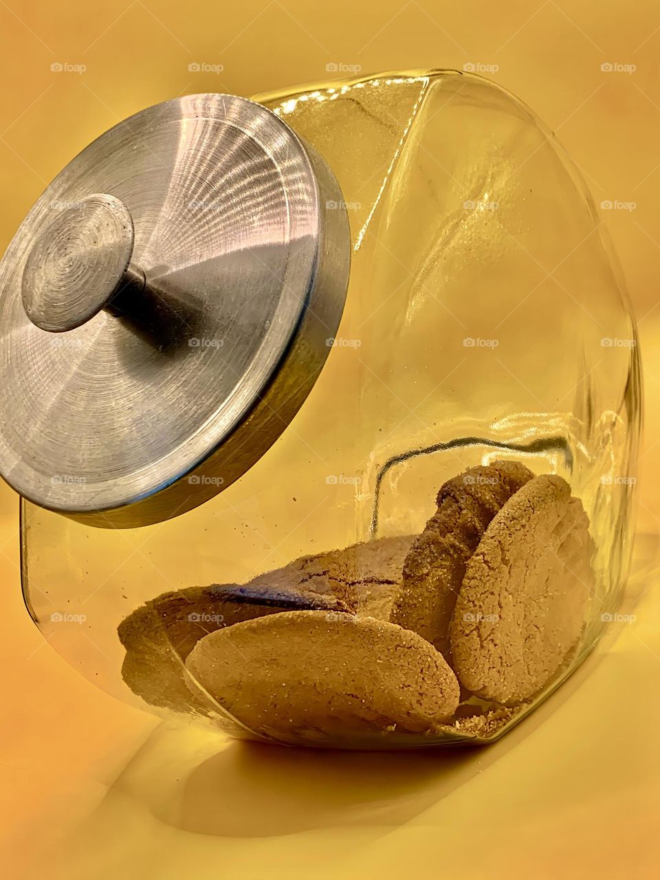 Ginger Cookies In The Sunshine Color Jar In Clear Glass With Metal Lid On Yellow Background.