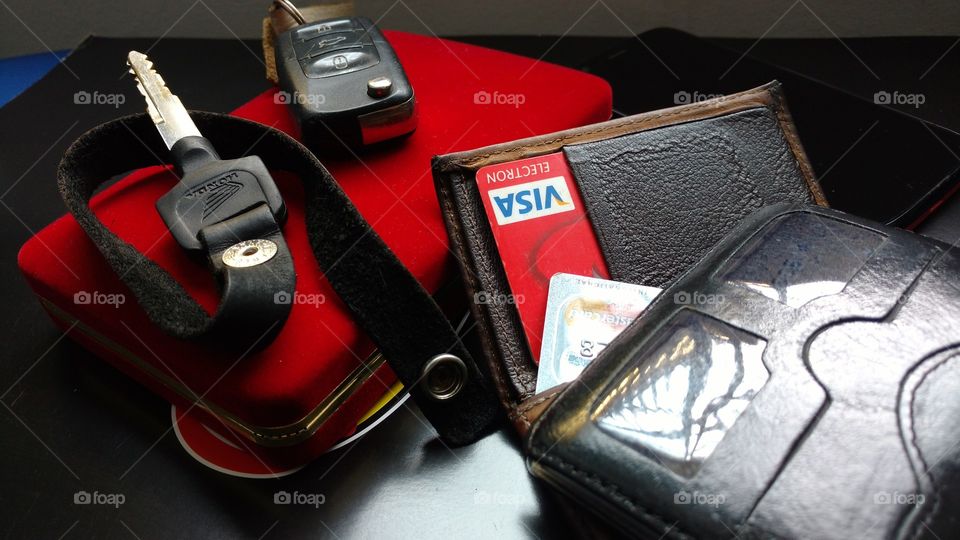 Escritório. Caixinha vermelha, cartões de créditos  Visa e Mastercard, carteira de dinheiro, chaves de carro e moto, sobre a mesa.