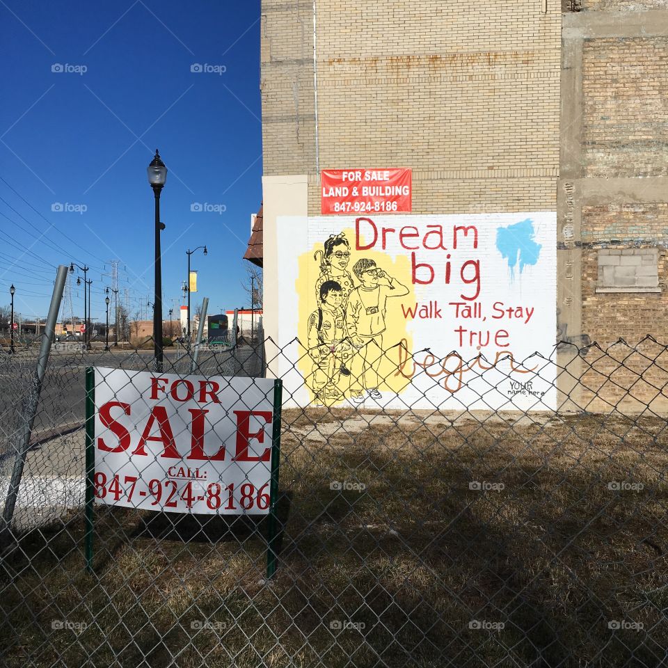“Dream big” mural next to a “For Sale” sign