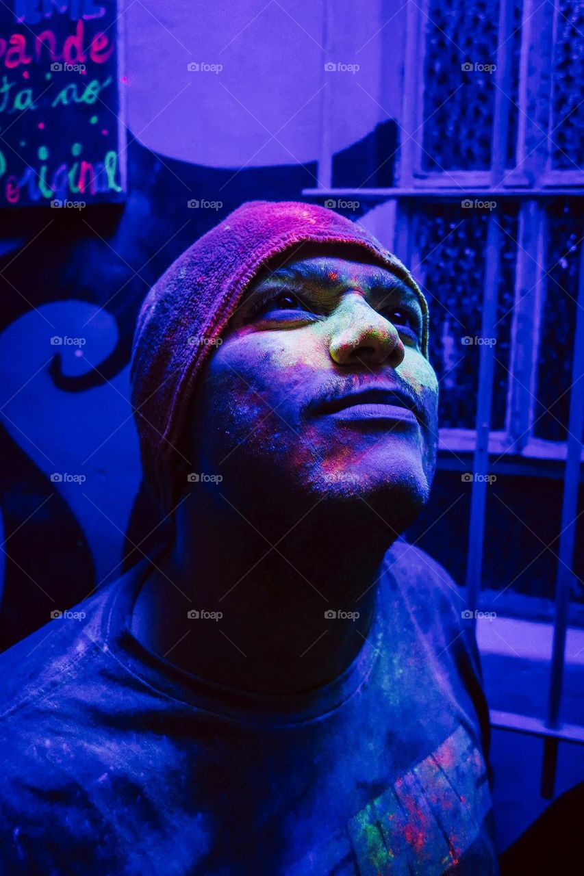 Beautiful Colorful Portrait of a Man with a black light and neon colors on the face. Blue Portrait with green and orange neon details.