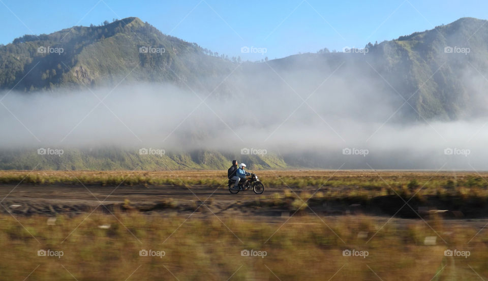 A biker riding across the plains below Mount Bromo in East Java, Indonesia