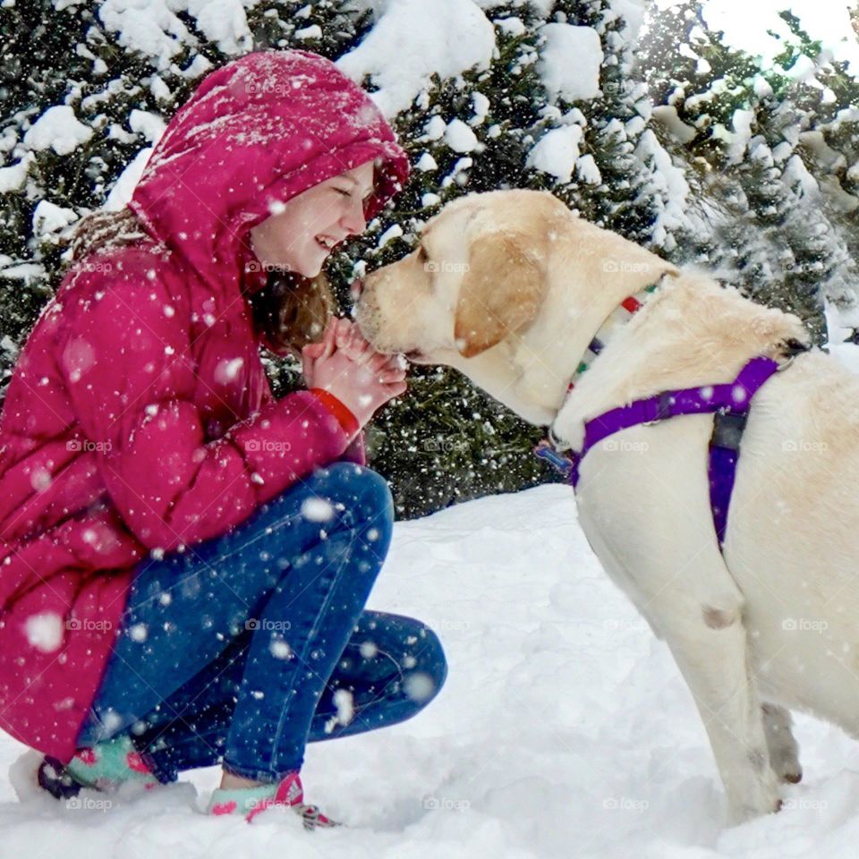 Snow falls all around girl and her dog 