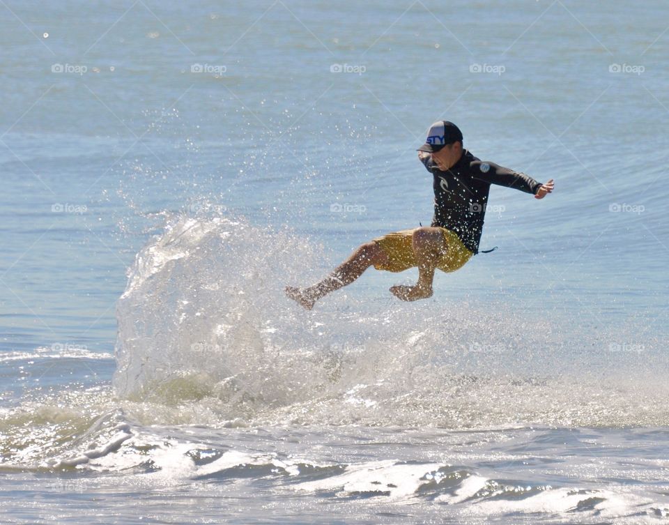 A man falling off his surf board making a big splash 