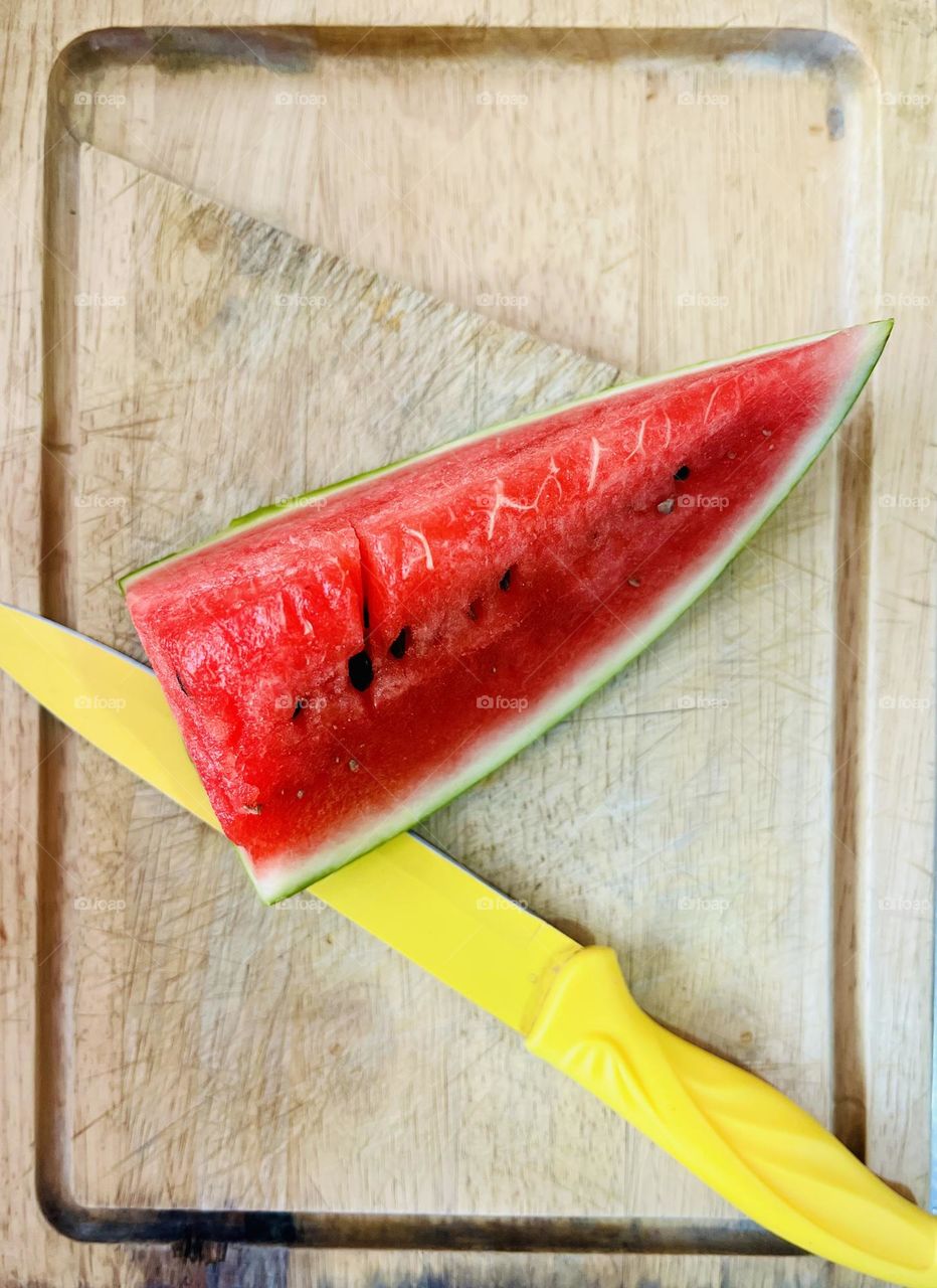 A yellow knife with a slice of watermelon 
