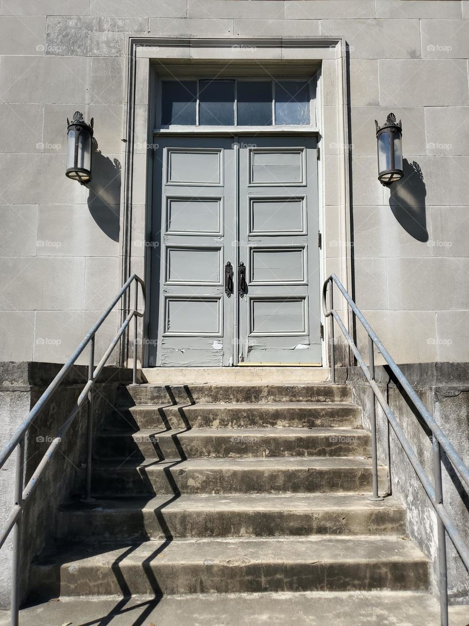 Stairs leading up to a double door entry with a transom window and lamps on each side. Rectangles everywhere!