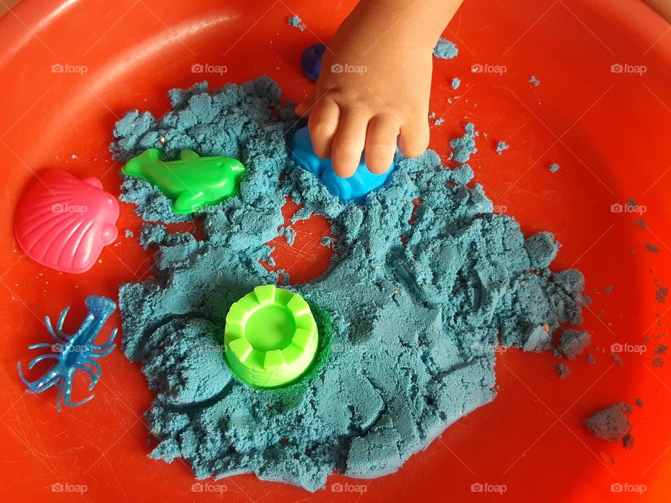 A hand of kid playing kinetic sand