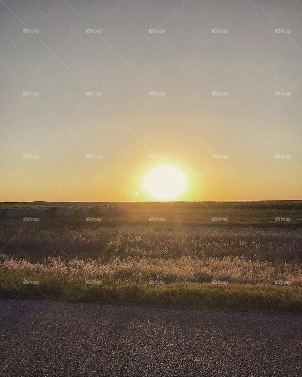 Kansas sun sinking down behind hay bails