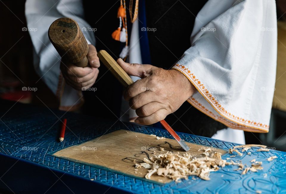 Man carving a wooden cross, for the Merry Cemetery located in Sapanta, Maramures, Romania.