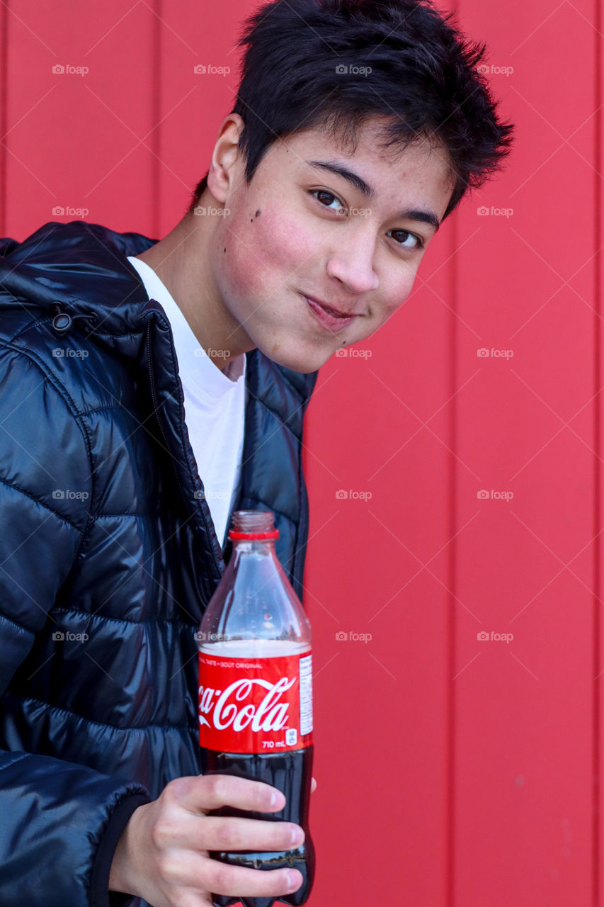 Young mischievous man with a bottle of a Coca-Cola