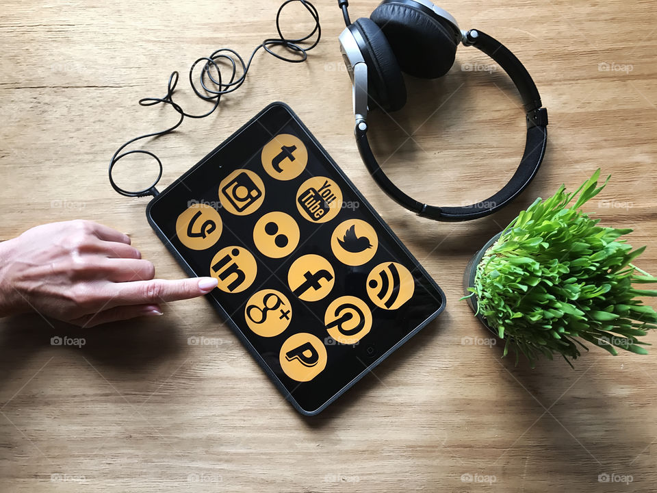 Female blogger using social media at the favorite tablet with headphones on wooden table 