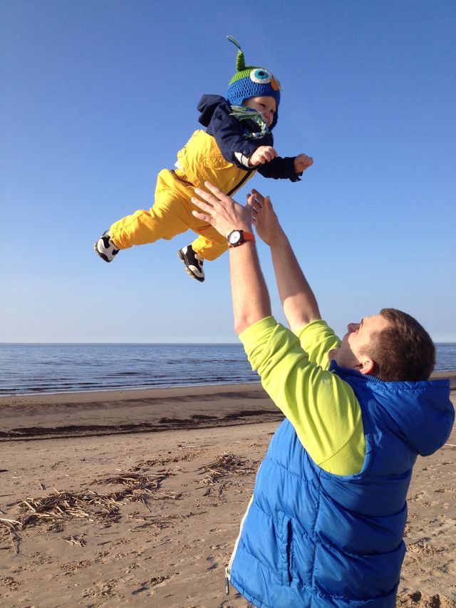 Man throwing his son in the air at beach