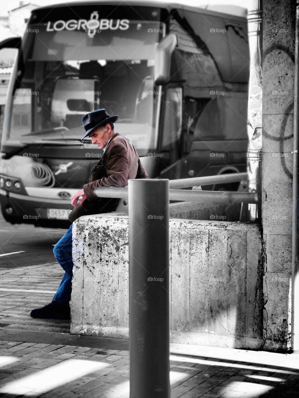 Man waits on a bus, man waits in the street, old man waiting on transportation, man in the city in Spain, black and white with color 