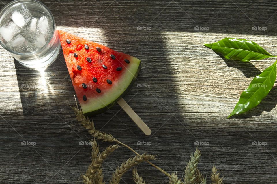 Portion of red watermelon with seeds in the form of a triangle on a wooden table surface