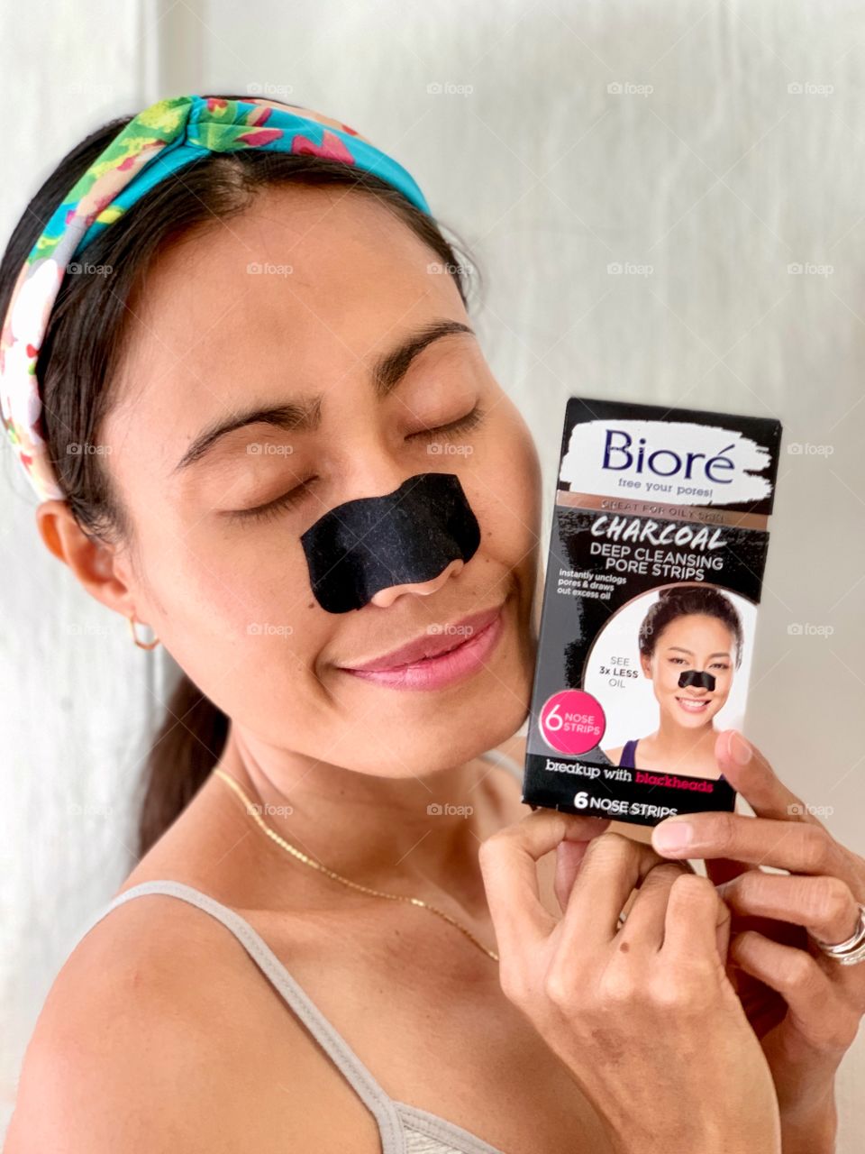 A woman using Bioré nose strips and holding the box of Bioré nose trips. Blackheads removal.