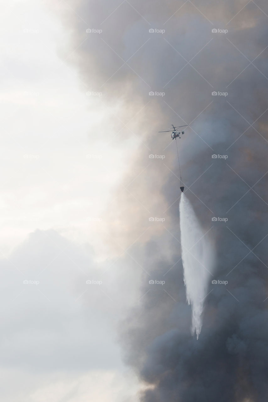 Helicopter of State emergency service is bringing the water to extinguish the fire