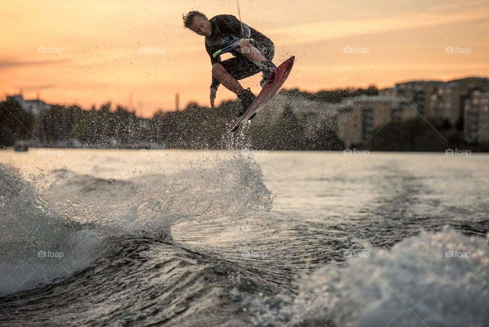 Man wakeboarding on sea at sunset