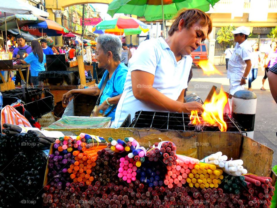 asian street vendor selling colored candles outside of quiapo church in quiapo, manila, philippines in asia