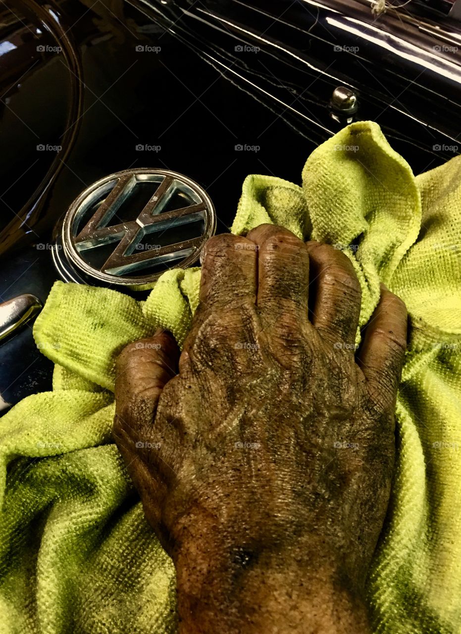 Mechanics dirty greasy hand cleaning up his VW bug. 