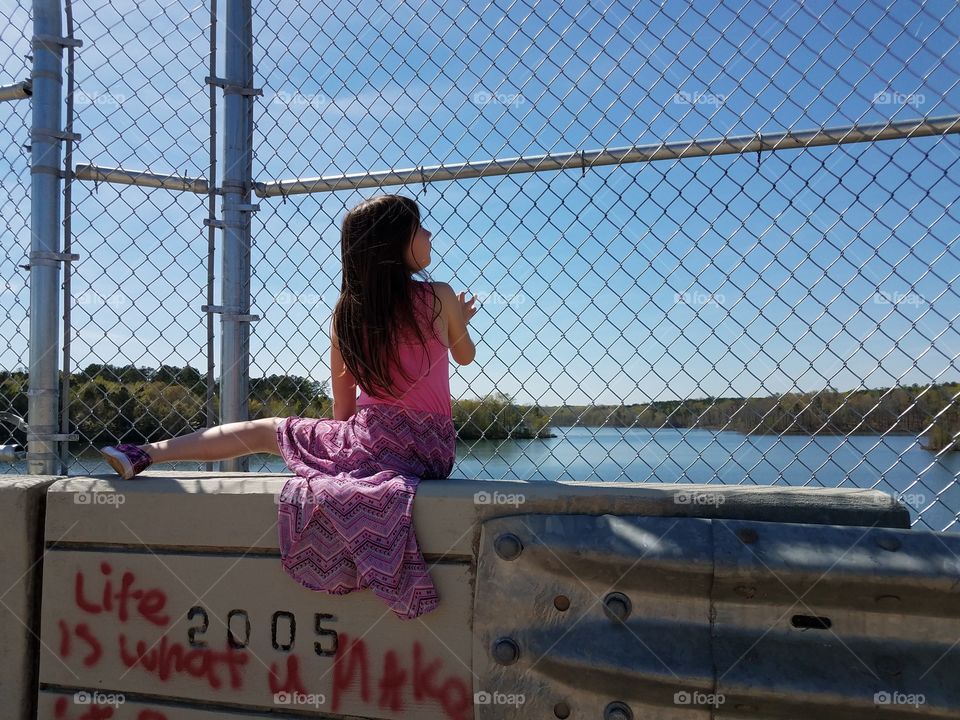 Cute little girl sitting near lake