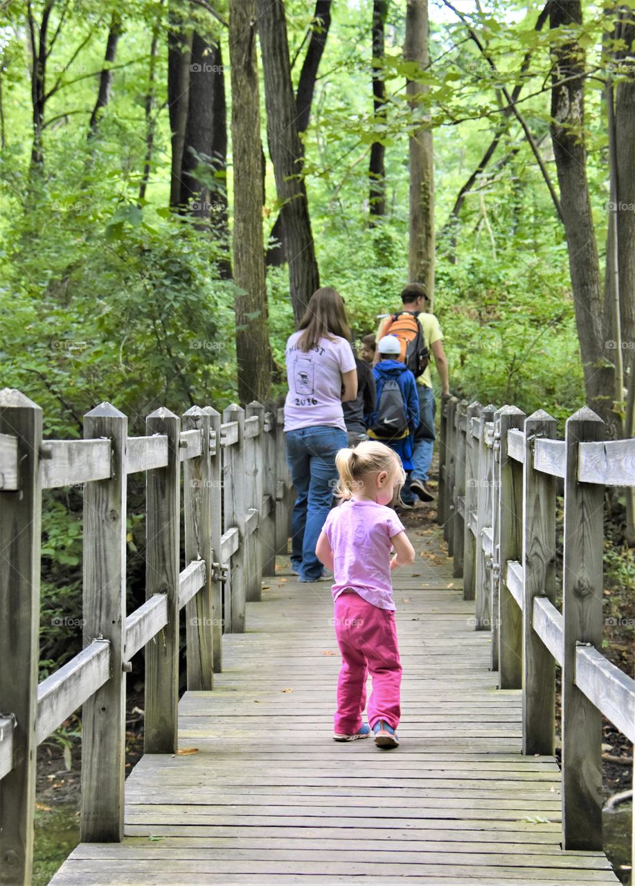Family hiking, crossing wooden bridge 