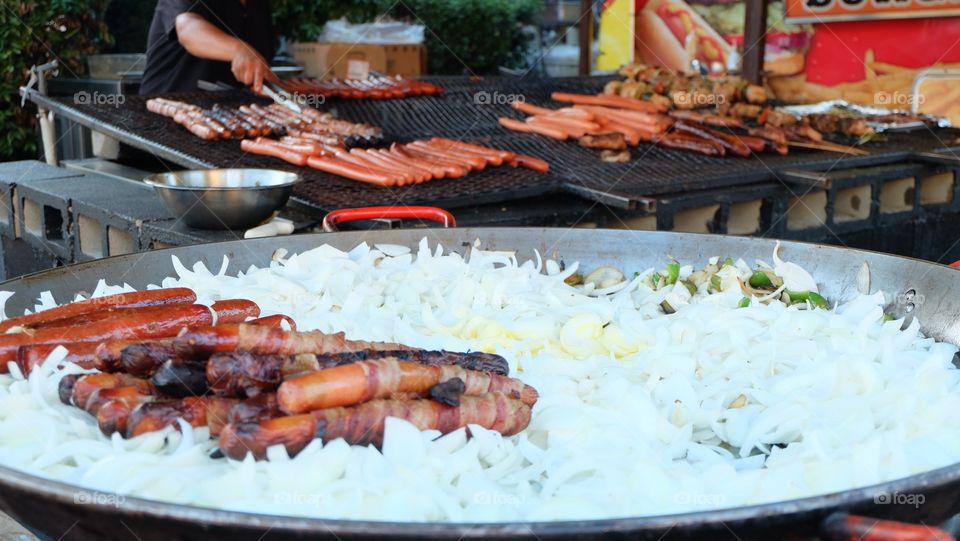 Man grilling frankfurters on a big wok