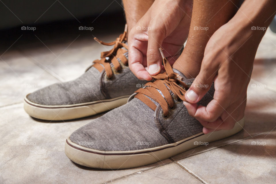 Young sportsman tying up tennis before going out to do running exercise in the morning