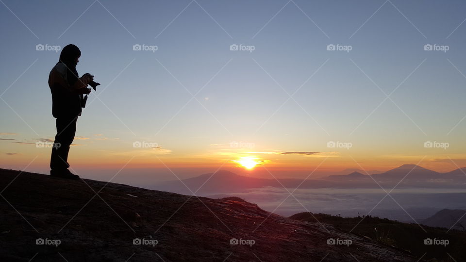 Silhouette of a photographer with sunrise as background, in Mount Prau, Indonesia