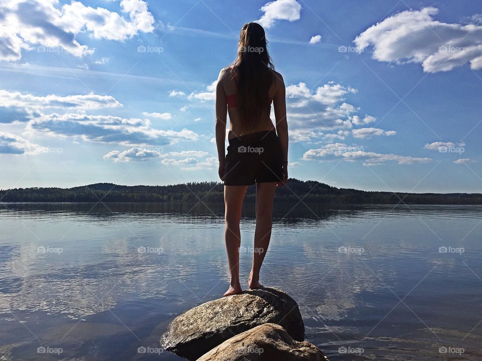 Rear view of a woman standing on rock in lake