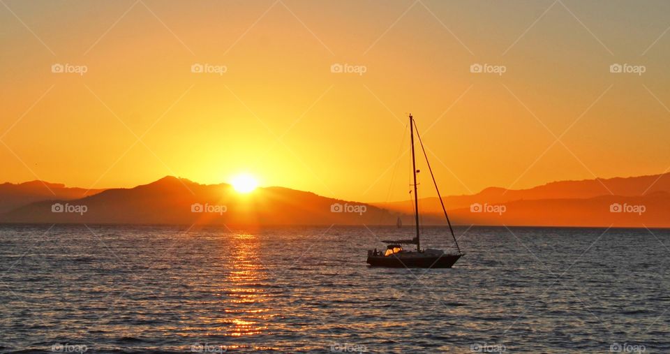 water scape sailboat sunset across the blue Waters