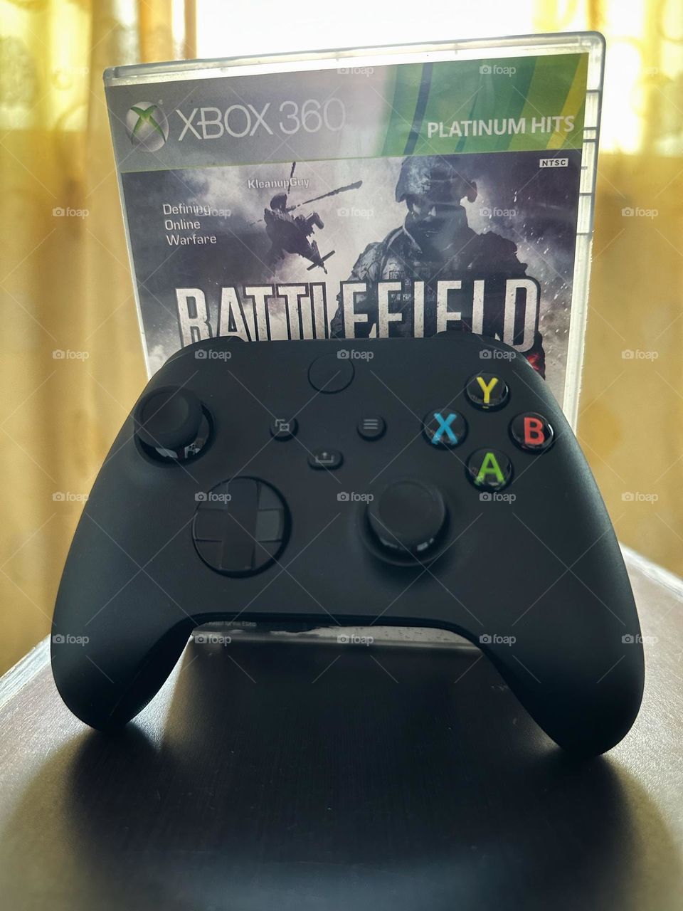 Battlefield video game box behind of a Xbox controller with natural light at the background.