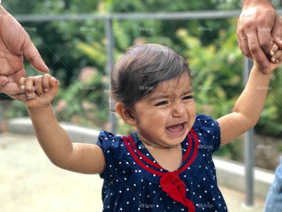 Girl holding her parent hand while crying