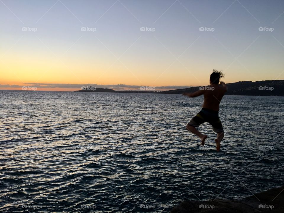 Jumping into the ocean at sunset in Hawaii 