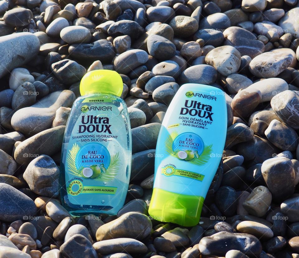 Garnier eau de coco shampoo and conditioner on the beach rocks.