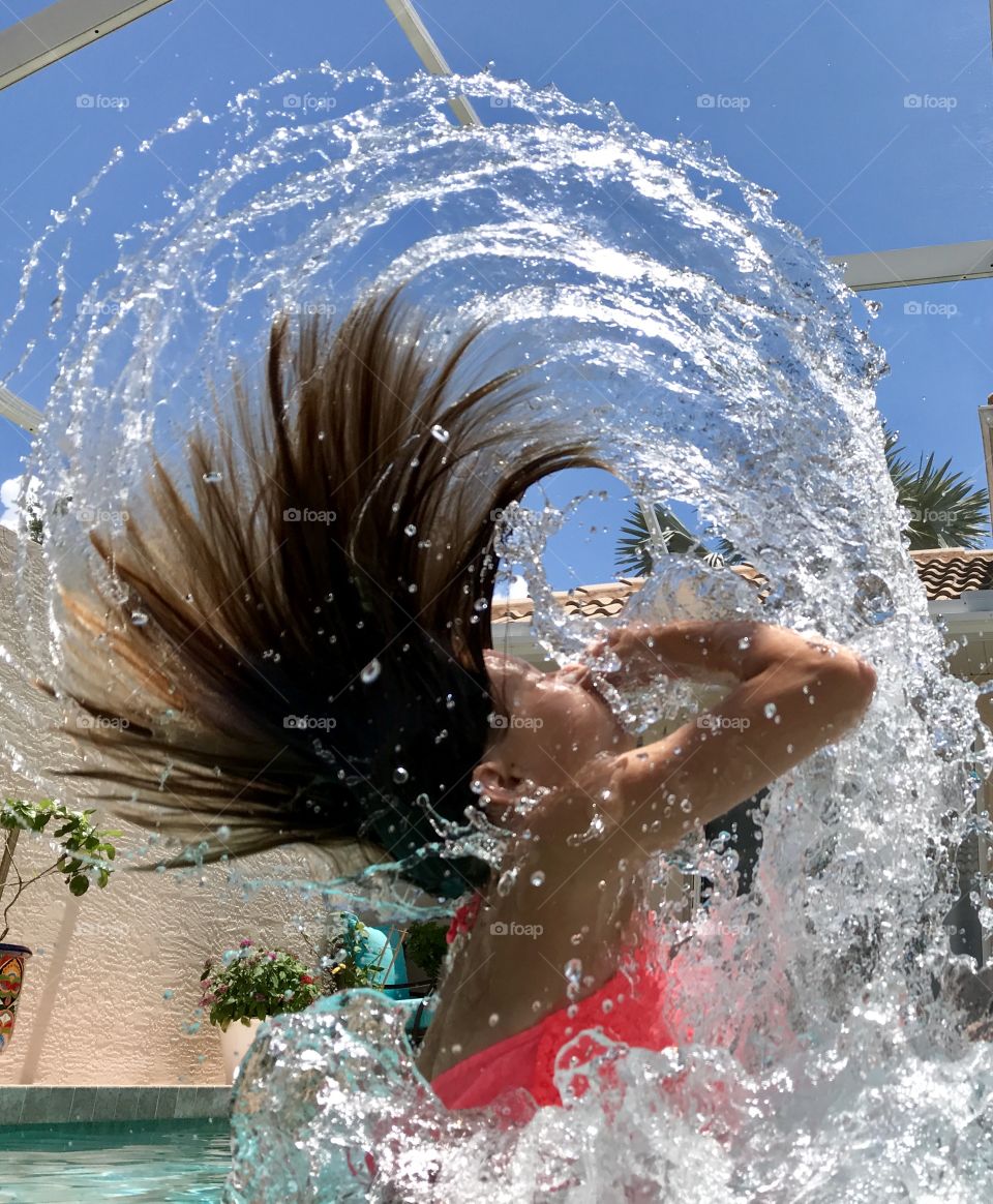 Giant hair and water wave in swimming pool capturing the sky and sunlight 