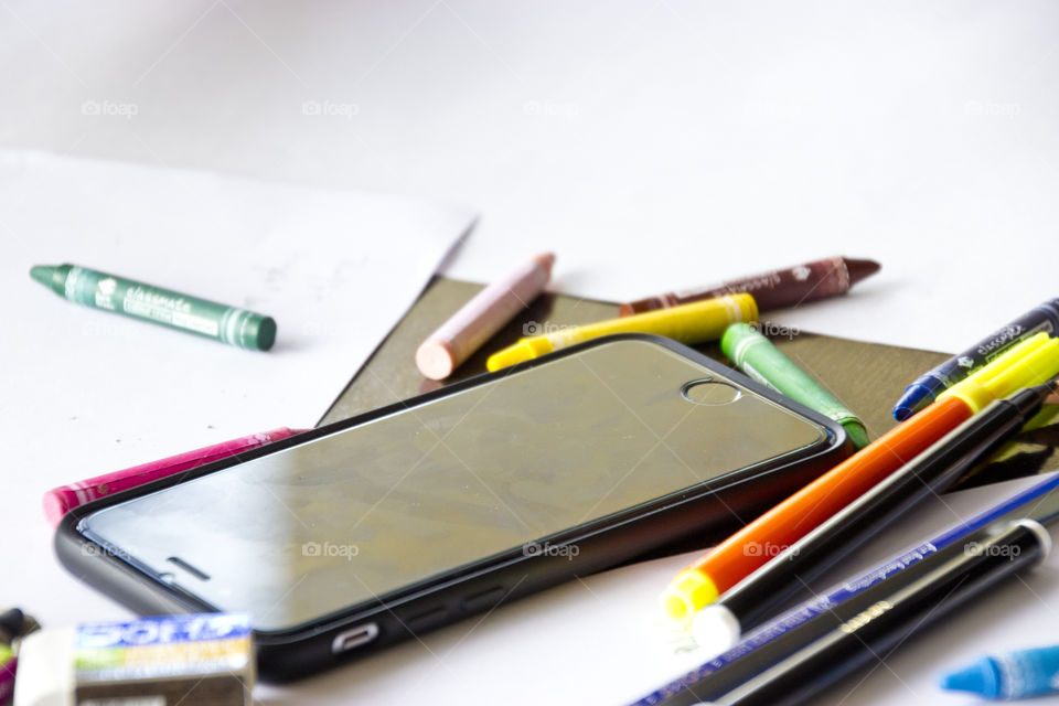 Smartphone phone and colorful crayons on table