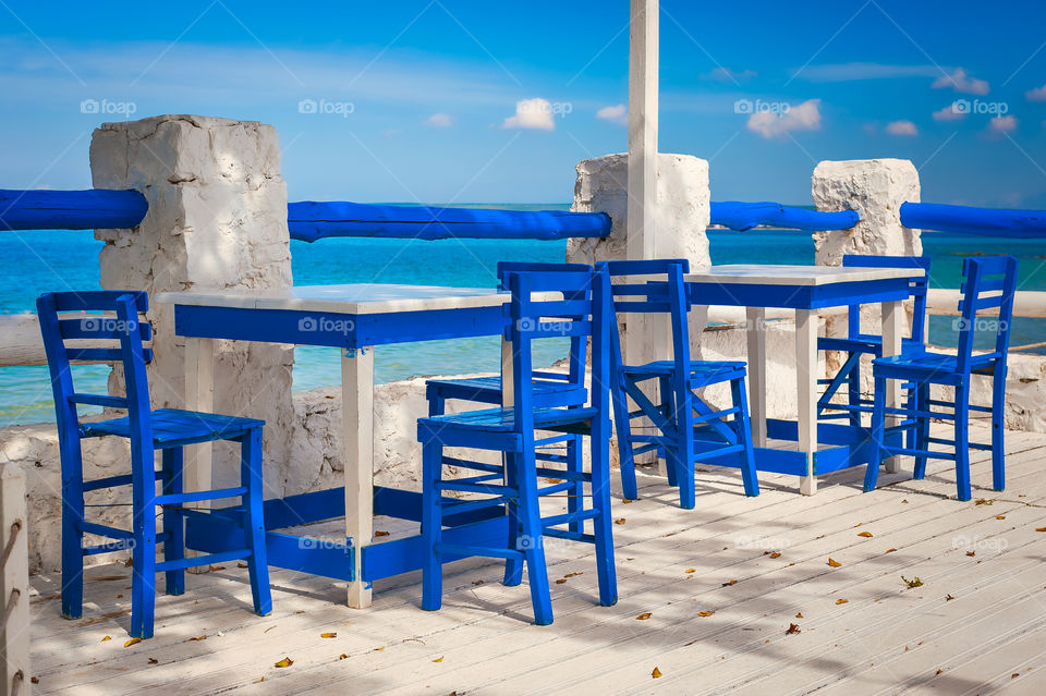 Blue chairs at a sea promenade.
