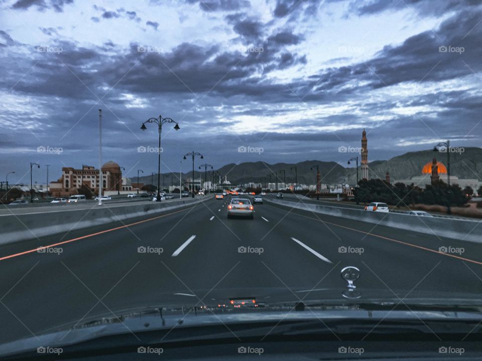 A point of view shot, taken from a car, for the Sultan Qaboos Highway, Muscat, on a rainy day. The Sultan Qaboos mosque landmark can be seen in the right side of the photo.