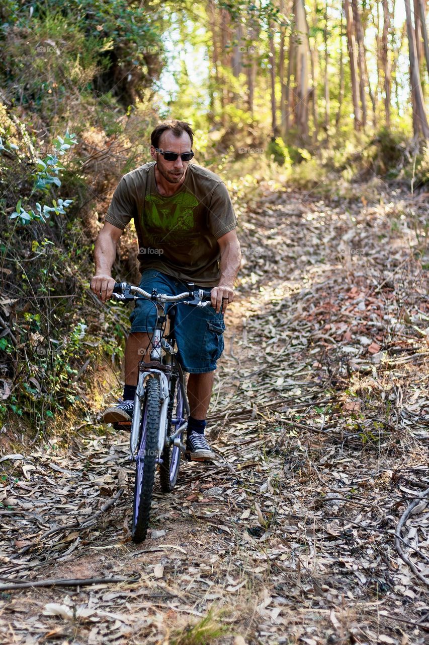 A man cycling through woodland trails