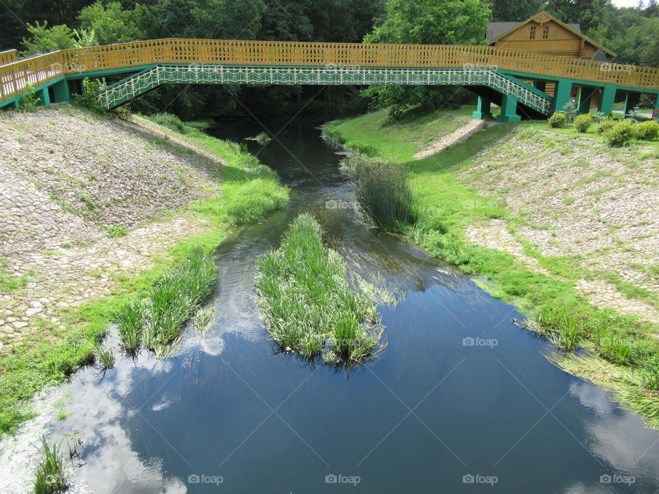 wooden bridge across the river in Russia, pilgrimage, orthodoxy, summer, clouds in the water