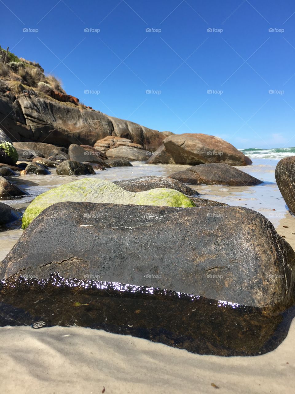 View of secluded remote wild beach from low ground perspective boulders rocks in foreground south Australia 