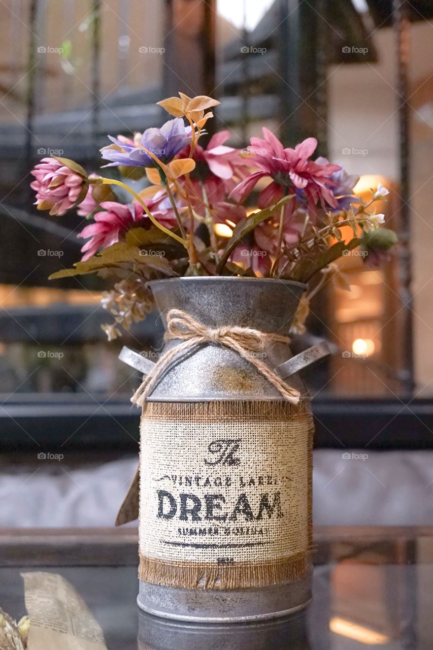 Artificial flowers in vintage aluminium milk can, for rustic interior decoration. Vintage style