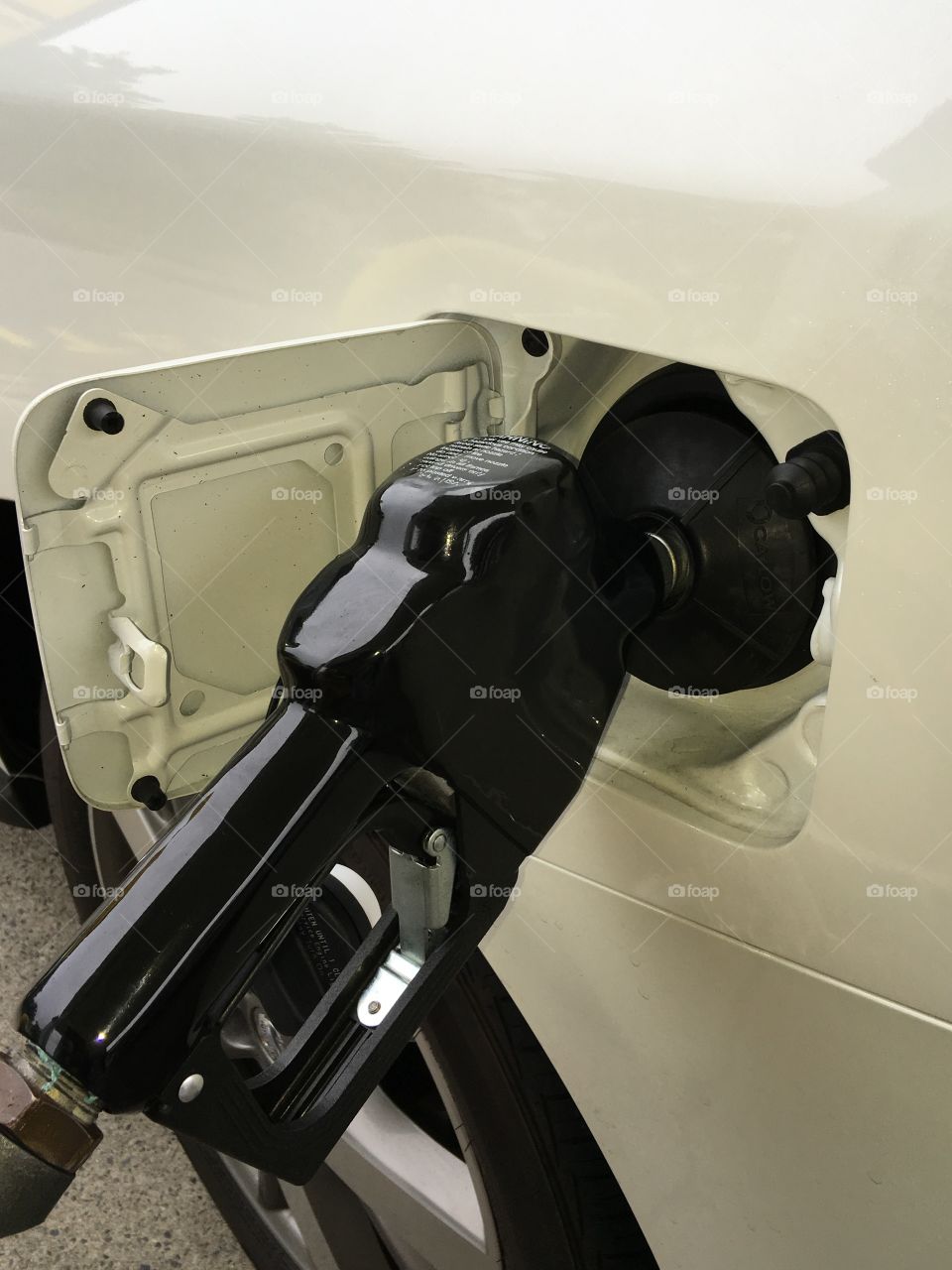 Black handle pumping gas into white car automatically.