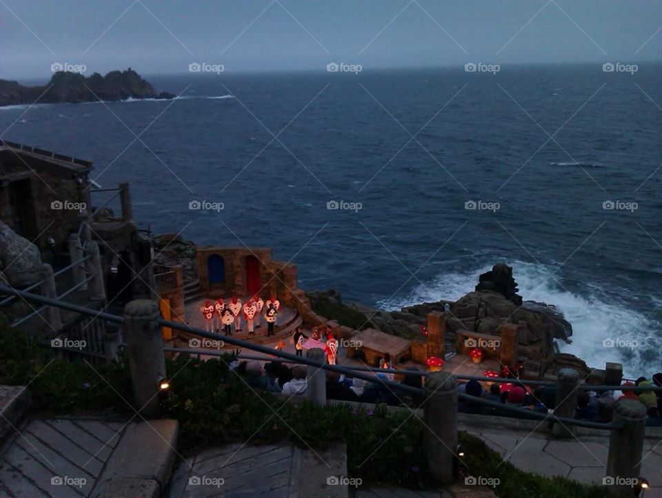 The Minack Theatre
Alice in wonderland performance 

 (Cornish: Gwaryjy Minack) is an open-air theatre, constructed above a gully with a rocky granite outcrop jutting into the sea (minack from Cornish meynek means a stony or rocky place). The theatre is at Porthcurno, 4 miles (6.4 km) from Land's End in Cornwall, England. The season runs each year from May to September, and by 2012 some 80,000 people a year see a show, and more than 100,000 pay an entrance fee to look around the site.  It has appeared in a listing of the world's most spectacular theatres.