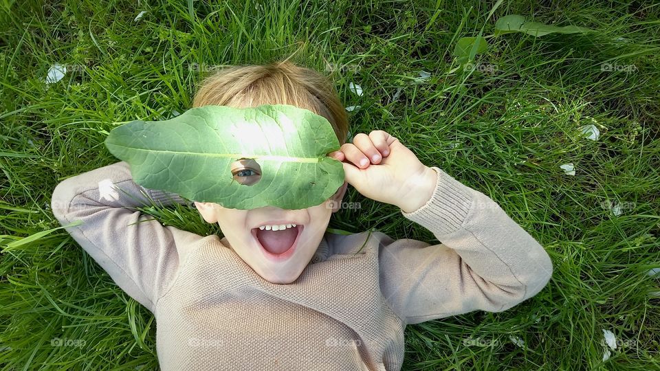 smiling little boy with a leaf on his face
