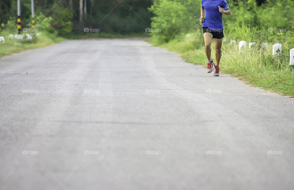 The men are running on the road Background light poles and trees.