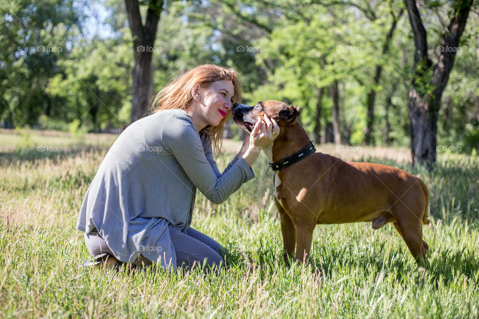 Girl with pitbull hugs in the park at summer day. The best friends. Happiness