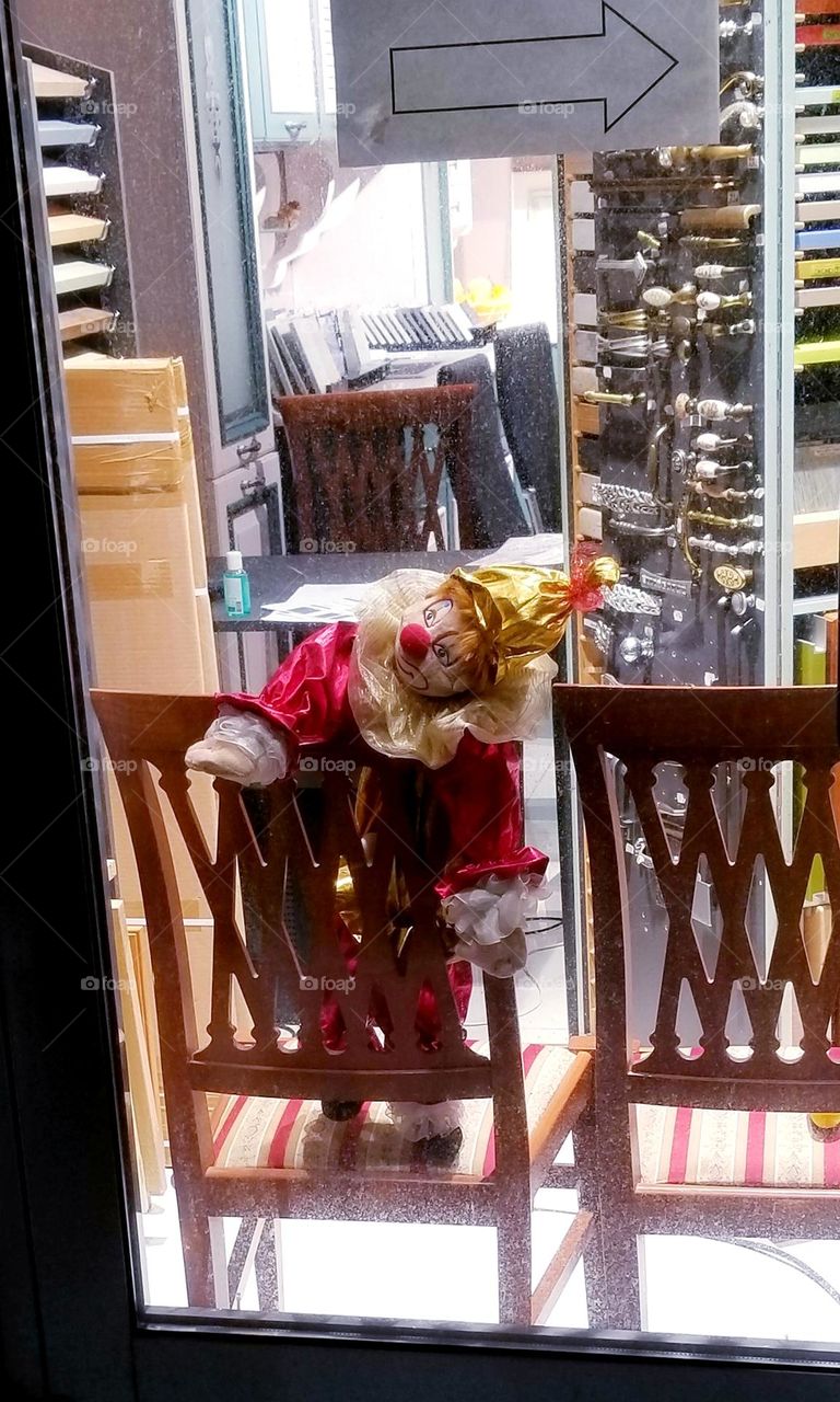 Doll sad clown in a shop window