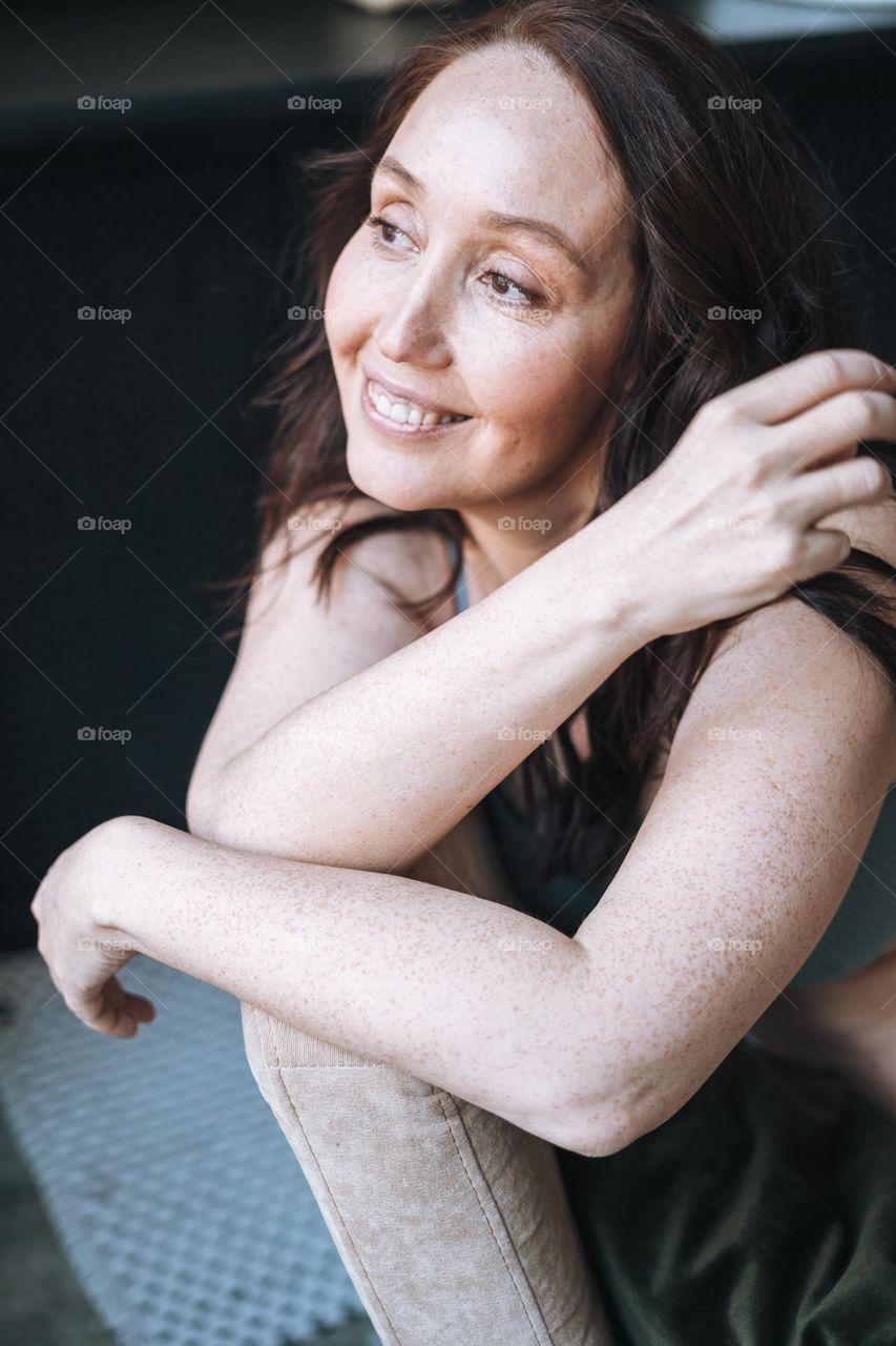 Adult brunette self loving forty years woman with natural skin with freckles and wrinkles at home 