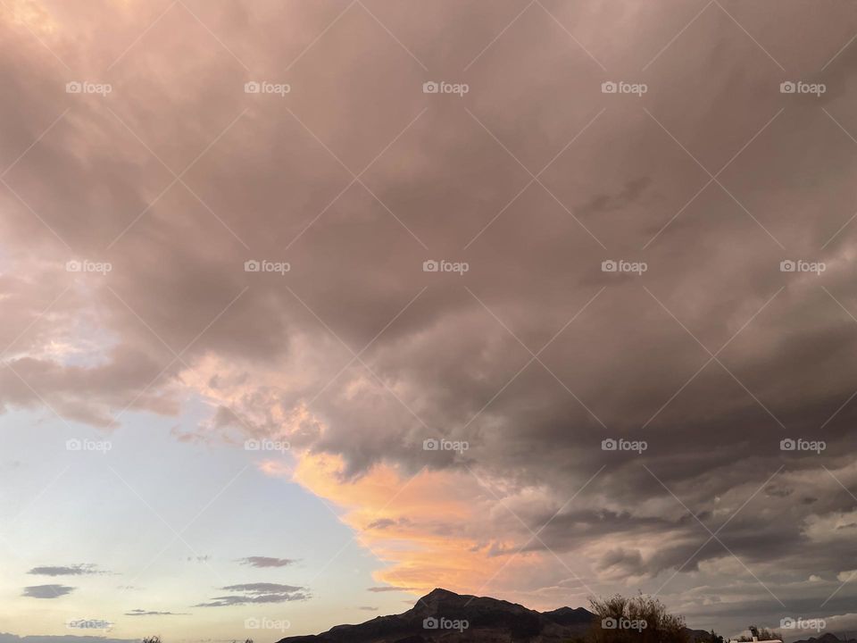 Several dark and pink clouds floating above a high mountains. 